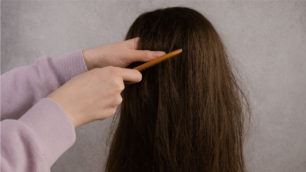 A woman is demonstrating how to care for a human hair wig